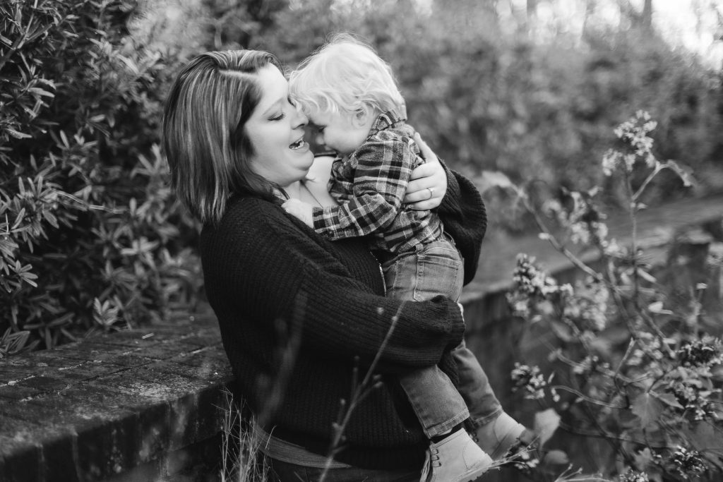 A black and white family portrait of a woman kissing her son at Quiet Waters Park.