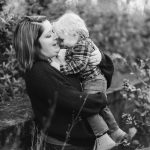 A black and white family portrait of a woman kissing her son at Quiet Waters Park.