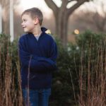 A young boy standing in front of tall grasses, captured at Quiet Waters Park for family portraits.