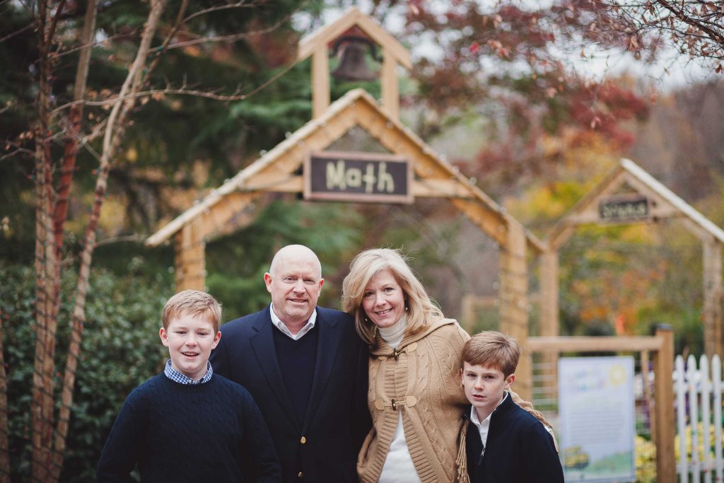 A family posing for a photo in front of a wooden gate at Brookside Gardens.