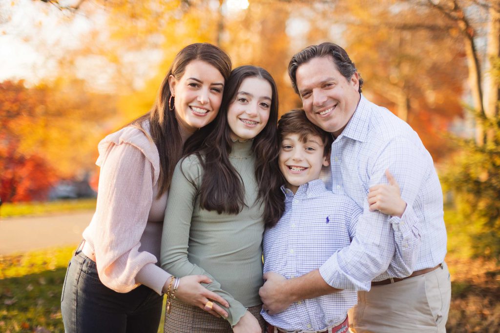 A family posing for a holiday photo in the fall at Federal Hill Park.