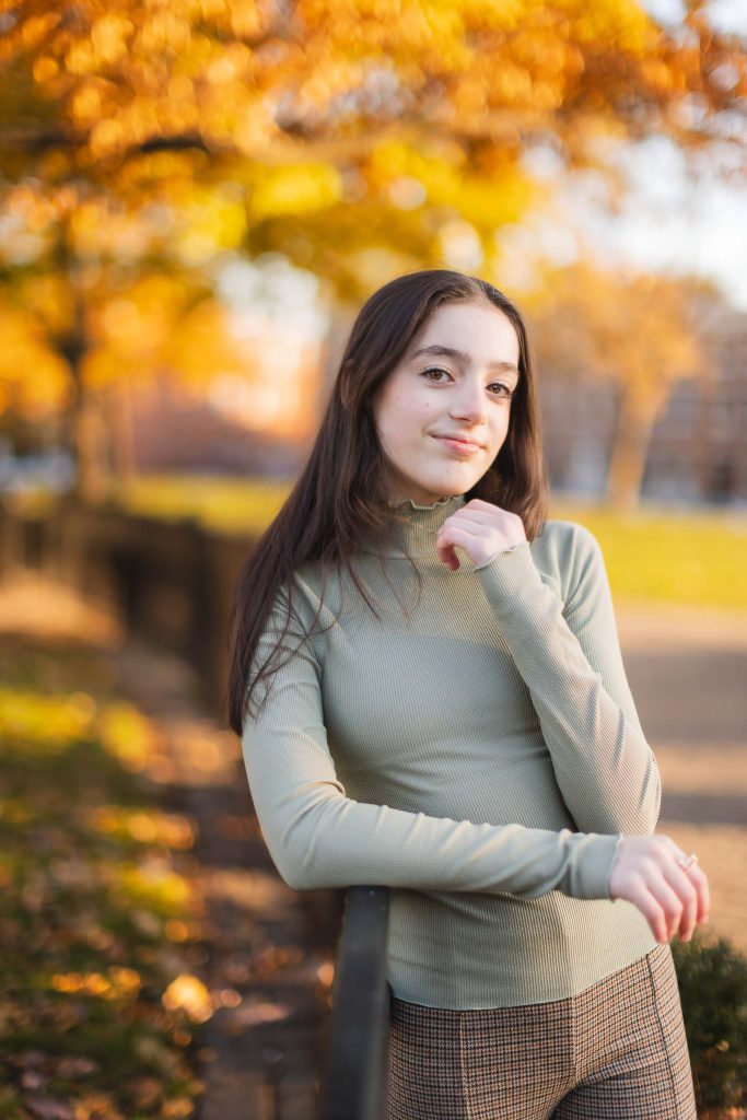 A young woman posing for a portrait on a railing in Federal Hill Park.