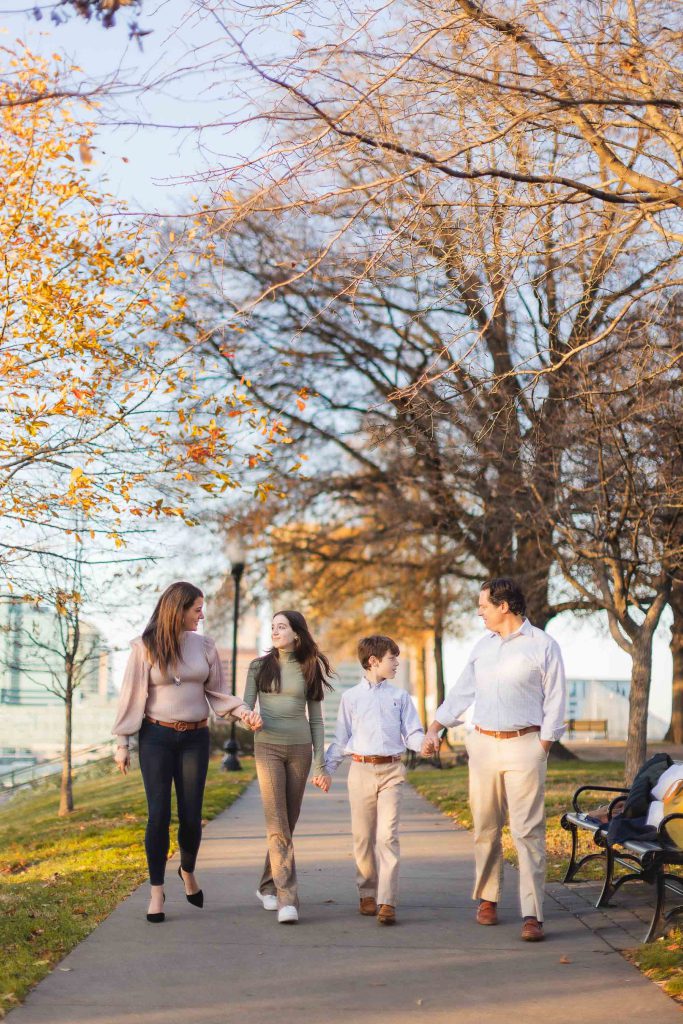 A family takes autumn portraits while strolling along the sidewalk near Federal Hill Park.