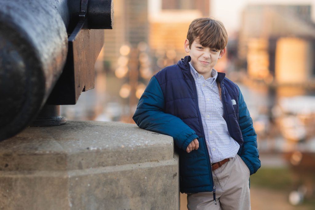 A boy is leaning against a cannon in Federal Hill Park.