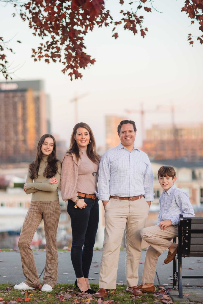 A family is posing for holiday portraits in Federal Hill Park.
