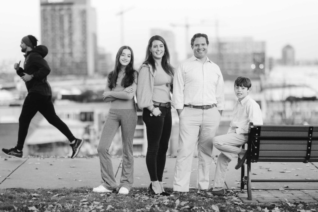 A black and white photo of a family posing on a bench in Federal Hill Park.