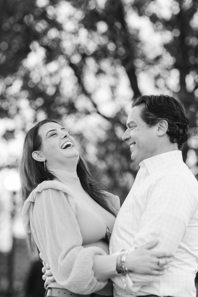 A black and white portrait of an engaged couple laughing in Baltimore.