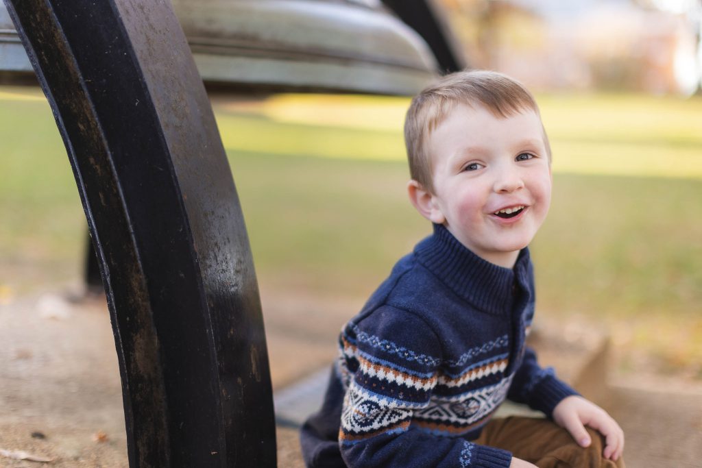 A young boy sits on the ground next to a metal bell in downtown Annapolis.