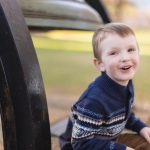 A young boy sits on the ground next to a metal bell in downtown Annapolis.