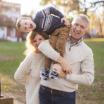 A family is holding a young boy in their arms in a Downtown Annapolis park.