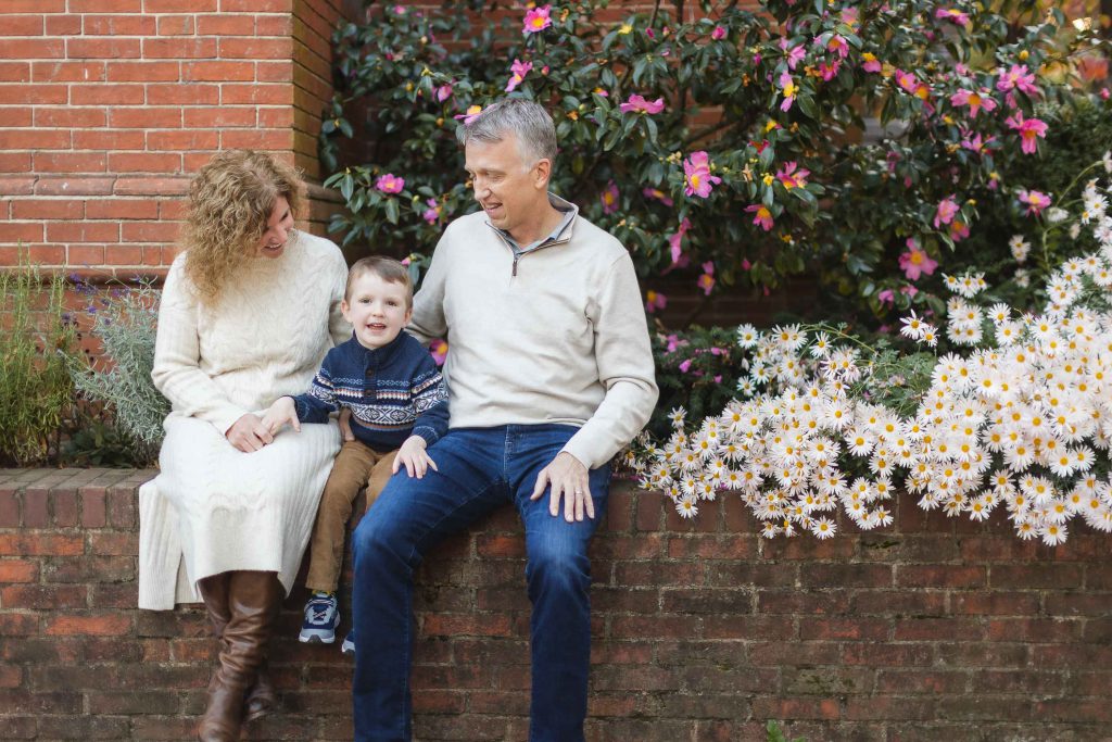 In Downtown Annapolis, a family poses for a portrait on a brick wall surrounded by flowers.