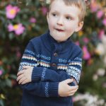 A young boy in a sweater standing in front of flowers in Downtown Annapolis.