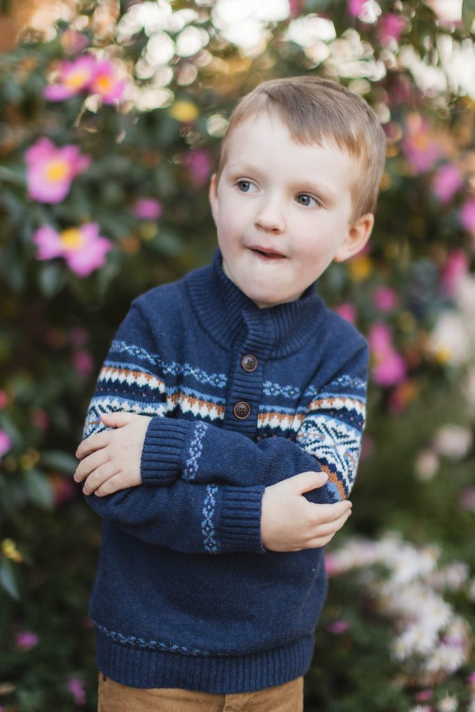A young boy in a sweater standing in front of flowers in Downtown Annapolis.