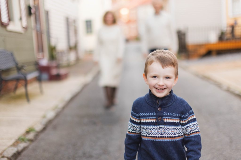 A young boy smiles while walking down a downtown street.