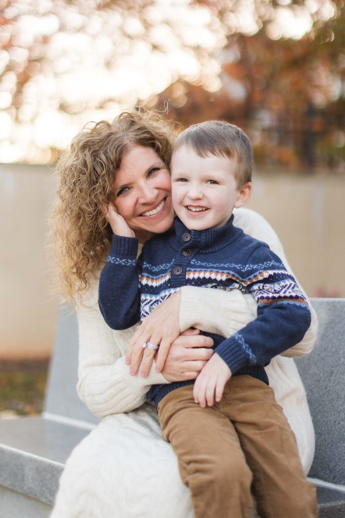 A family hugging on a bench in Downtown Annapolis, capturing a heartfelt portrait moment in the fall.