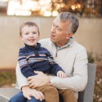 A father and son sitting on a bench in downtown Annapolis, enjoying the fall season.