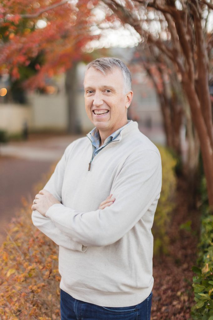 A man with his arms crossed in front of a downtown Annapolis tree.