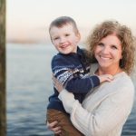 A woman holding a young boy in front of a dock in Downtown Annapolis.