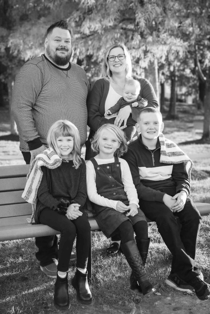 A black and white family portrait captured during sunset.