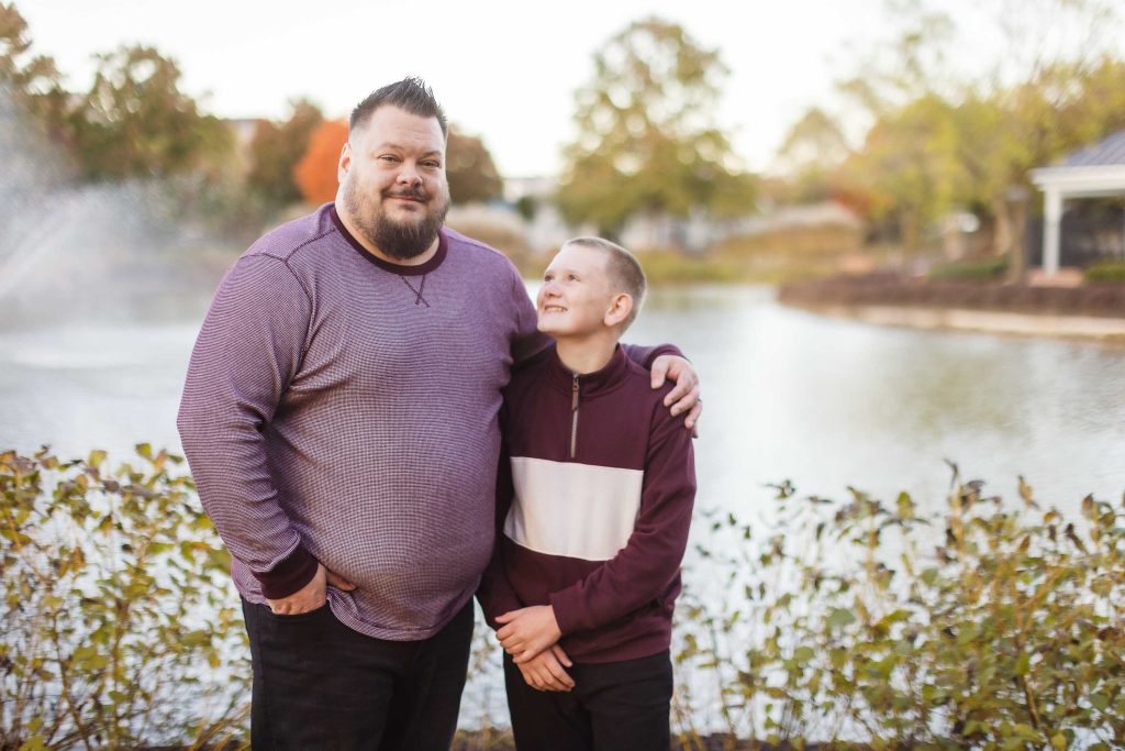 A family standing in front of a pond during sunset.