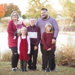 A family posing in front of a serene pond at sunset while capturing beautiful family portraits.