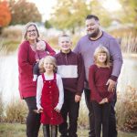 A family posing for a sunset portrait in front of a pond.