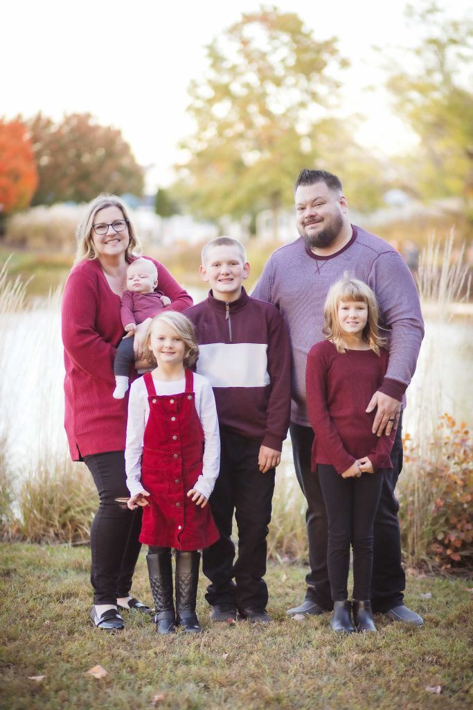 A family posing for a sunset portrait in front of a pond.