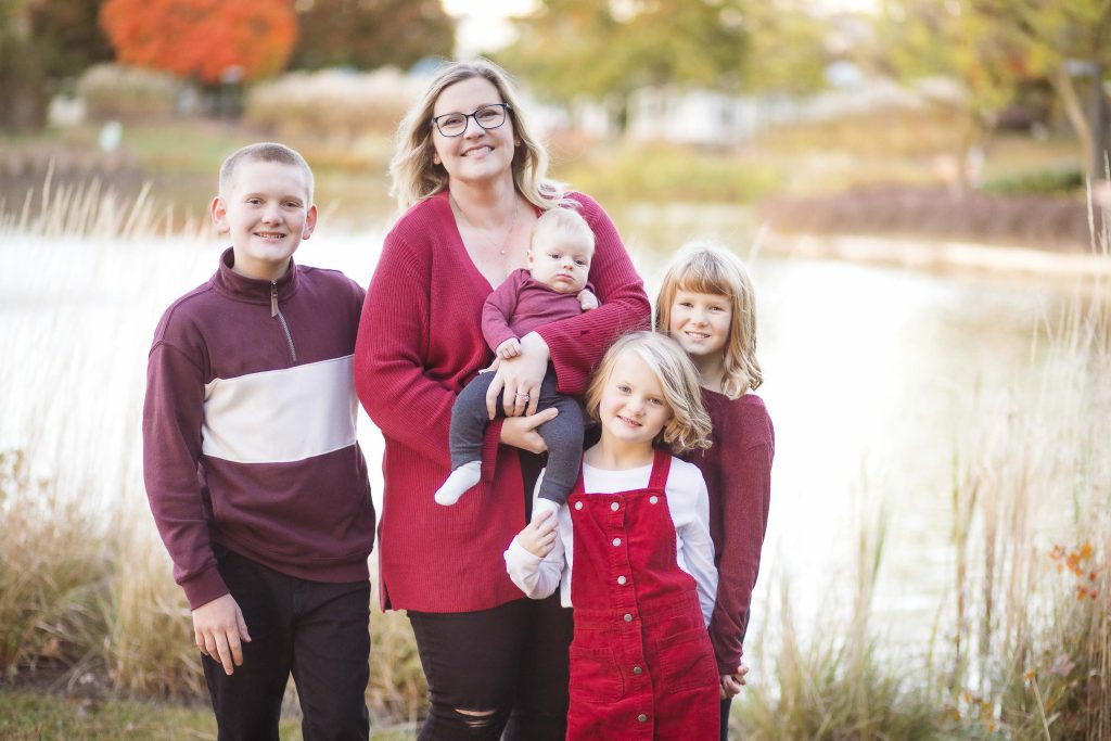 A family is posing for a portrait in front of a serene pond during sunset.
