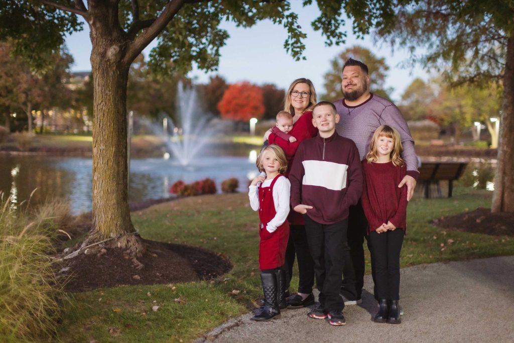 A family posing for a sunset portrait in front of a pond.