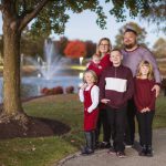 A family posing for a sunset portrait in front of a pond.