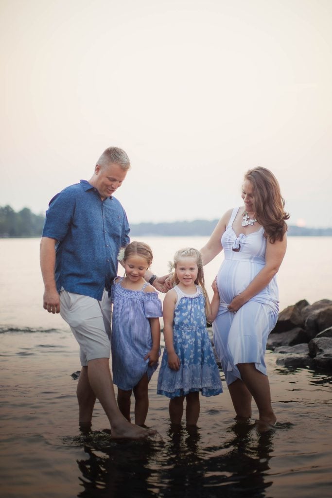A family is standing in the water at sunset during a Maryland portrait Photography session.
