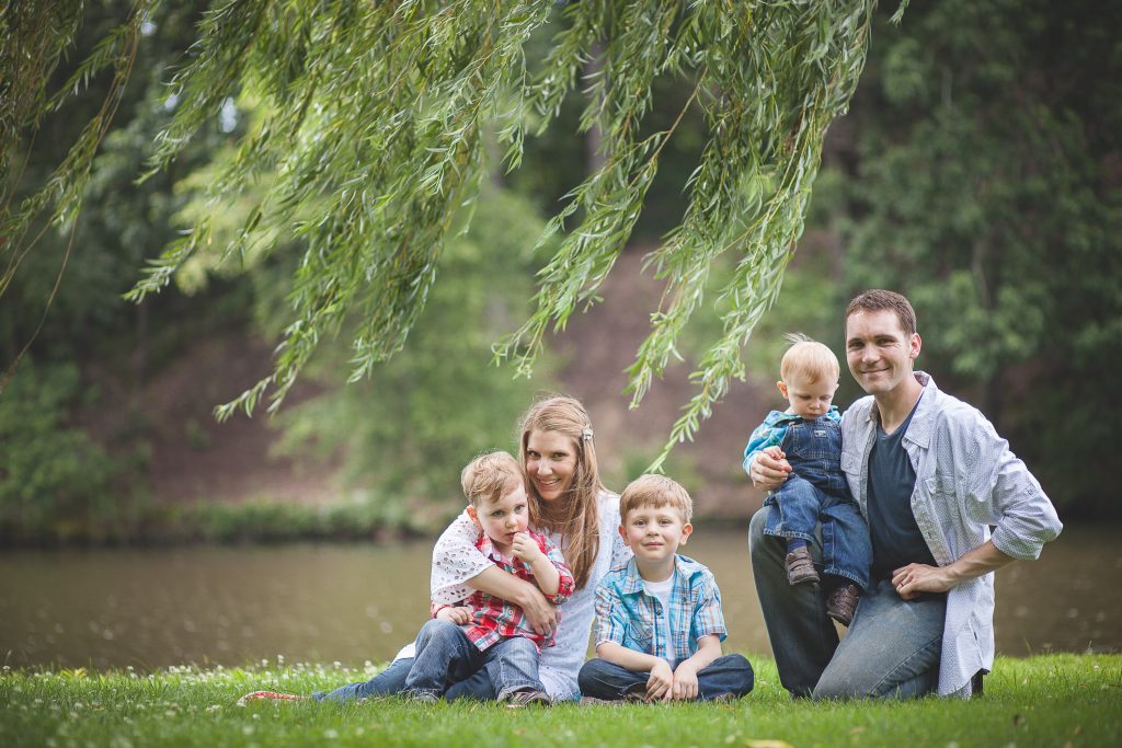A family sits on the grass under a willow tree at Allen Pond in Bowie, Maryland.
