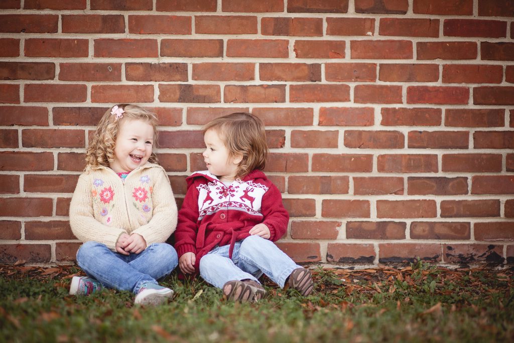 Two children sitting in front of a brick wall at Allen Pond in Maryland.
