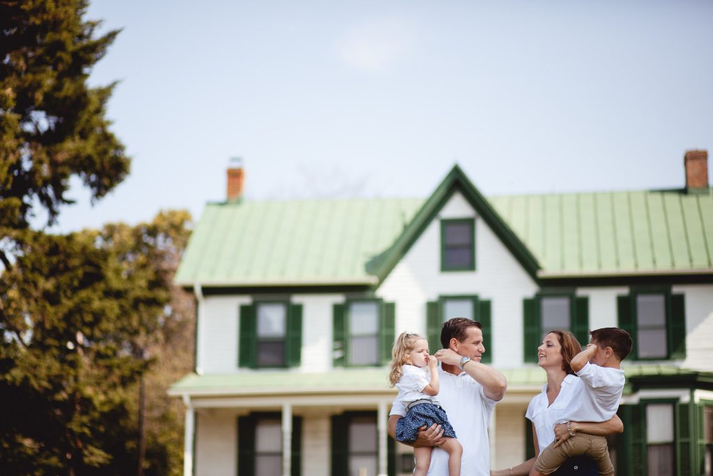 A family is standing in front of a green house at Agricultural History Farm Park in Maryland.