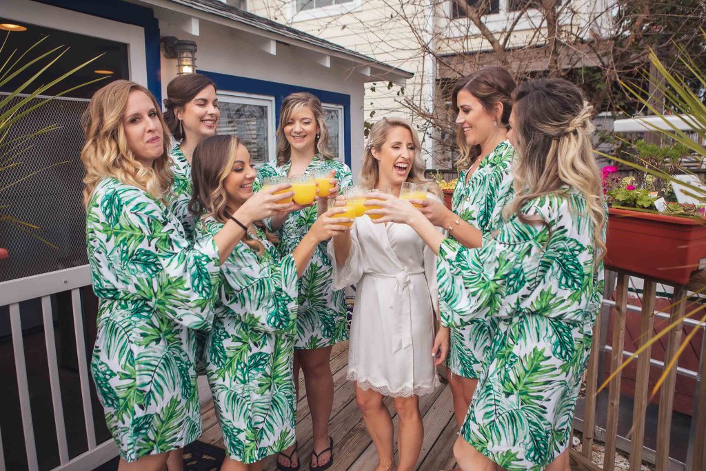 A group of bridesmaids in green robes on a deck at Annapolis Maritime Museum.