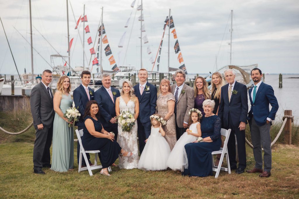 A wedding party posing in front of sailboats at the Annapolis Maritime Museum in Maryland.