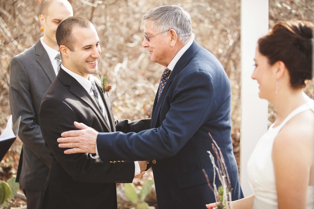 A man shakes hands with his father during an Annapolis wedding ceremony.