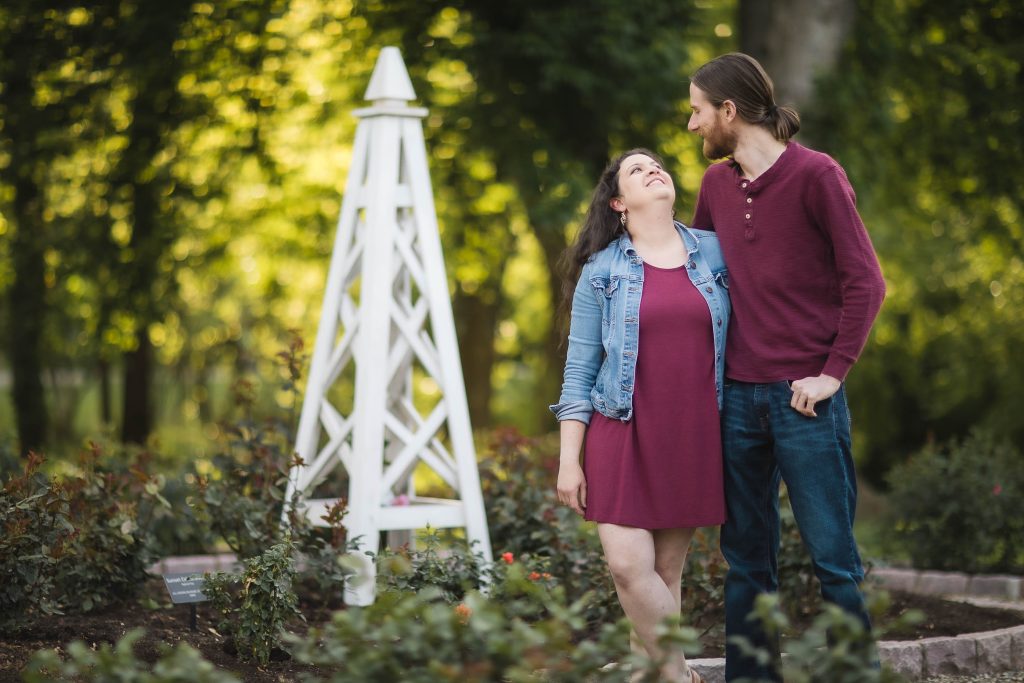 An engaged couple standing in front of the Bonair Rose Garden.