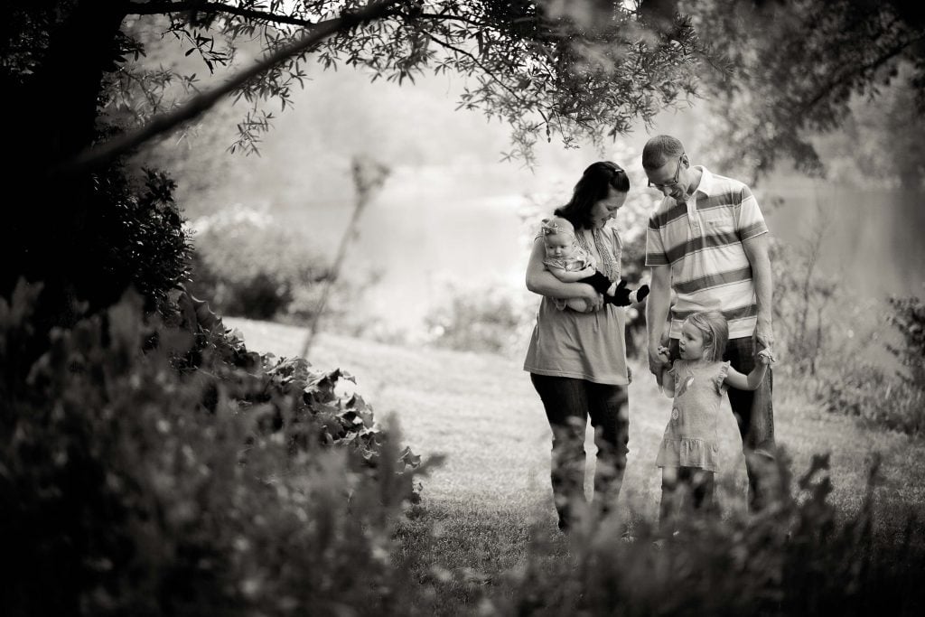 A black and white photo of a family standing in the grass at Buddy Attick Lake Park in Maryland's Greenbelt.