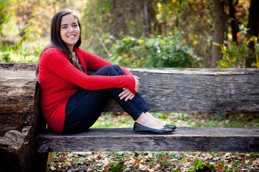 A woman sitting on a bench at Buddy Attick Lake Park in Maryland during the fall.
