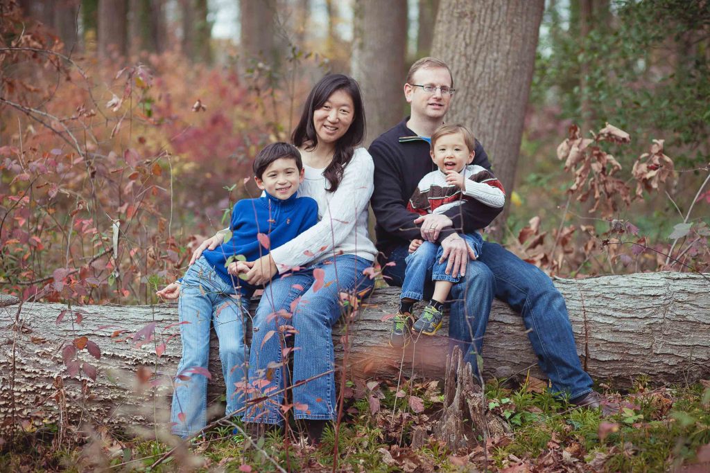 A family enjoys nature at Buddy Attick Lake Park in Greenbelt, Maryland as they sit on a fallen tree.