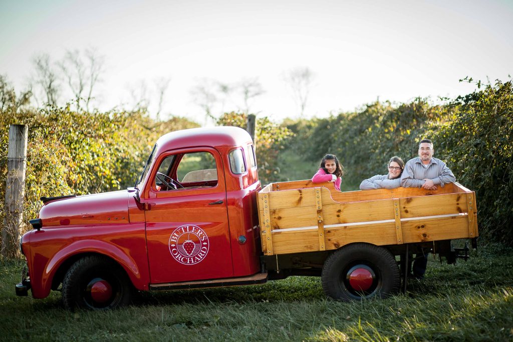 A family sits in the back of a red truck at Butler's Orchard, Germantown.