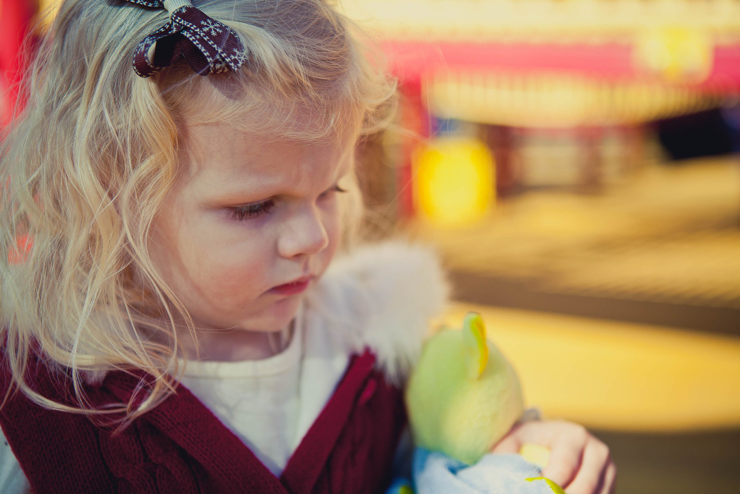 A little girl holding a stuffed animal at Clemyjontri Park in McLean, Virginia.