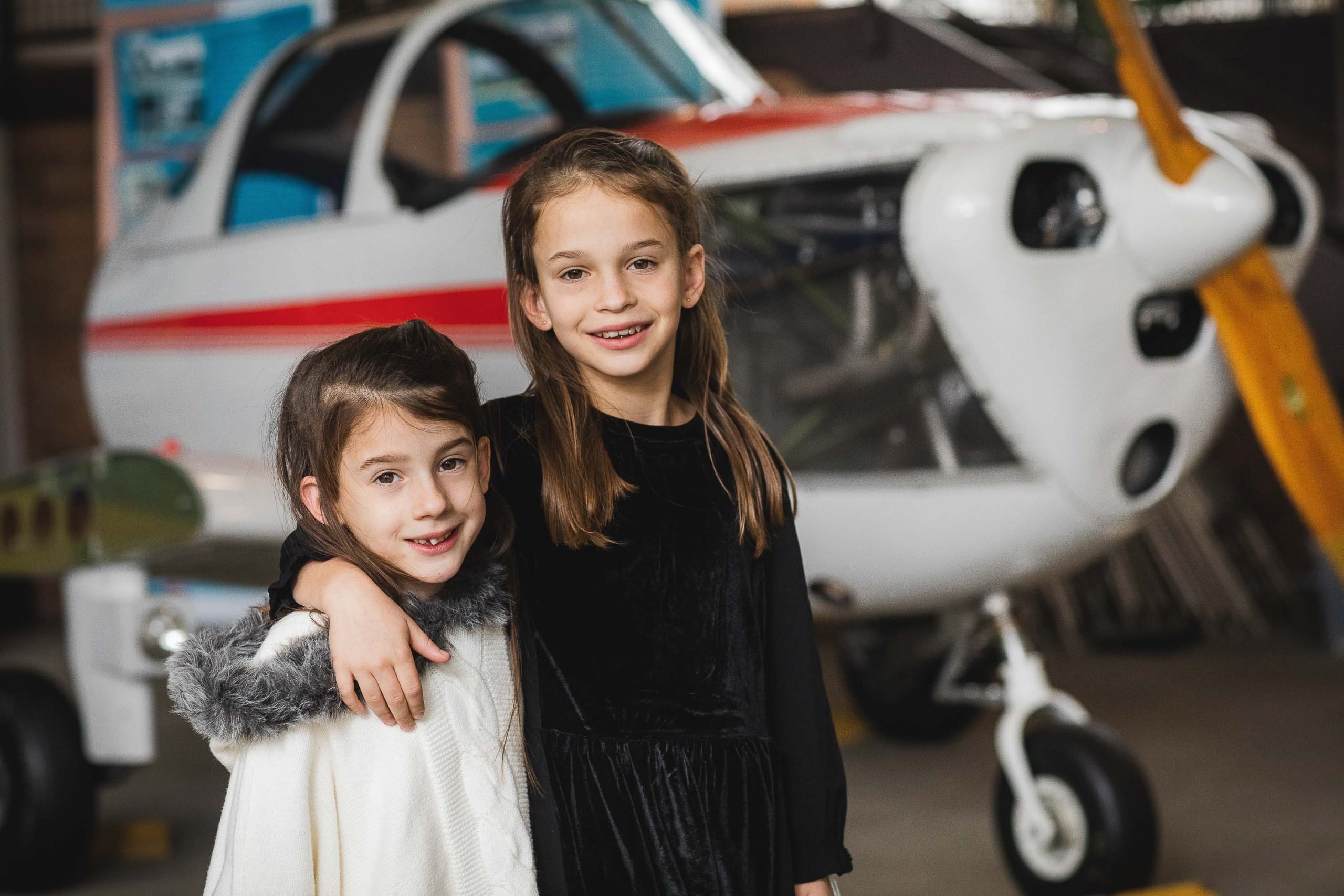 Two girls posing in front of an airplane at the College Park Aviation Museum.