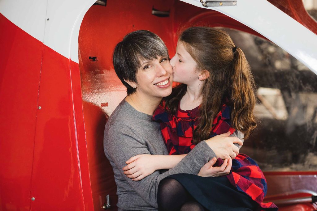 A mother and daughter hugging in a red helicopter at College Park Aviation Museum.