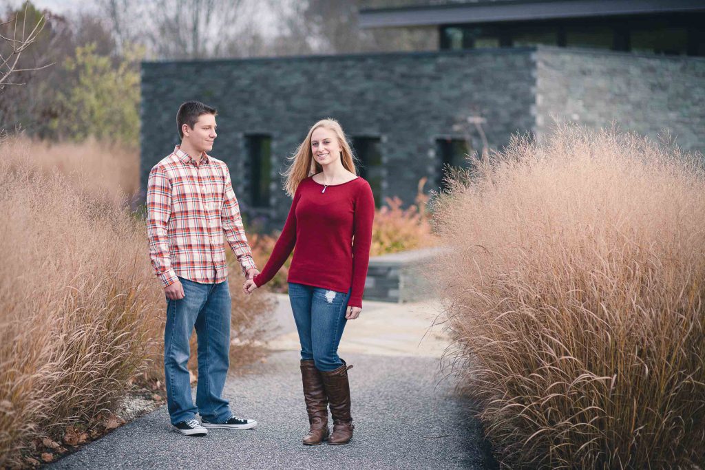 A couple holding hands in front of tall grasses at Cylburn Arboretum.