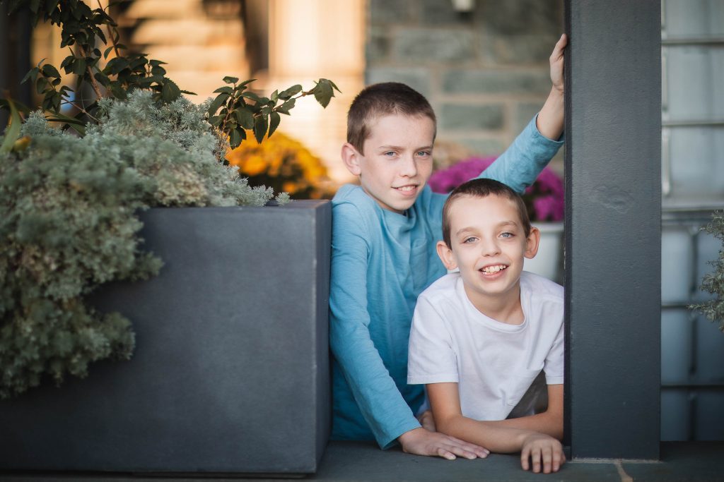 Two boys leaning out of a window in front of a house in Washington DC.