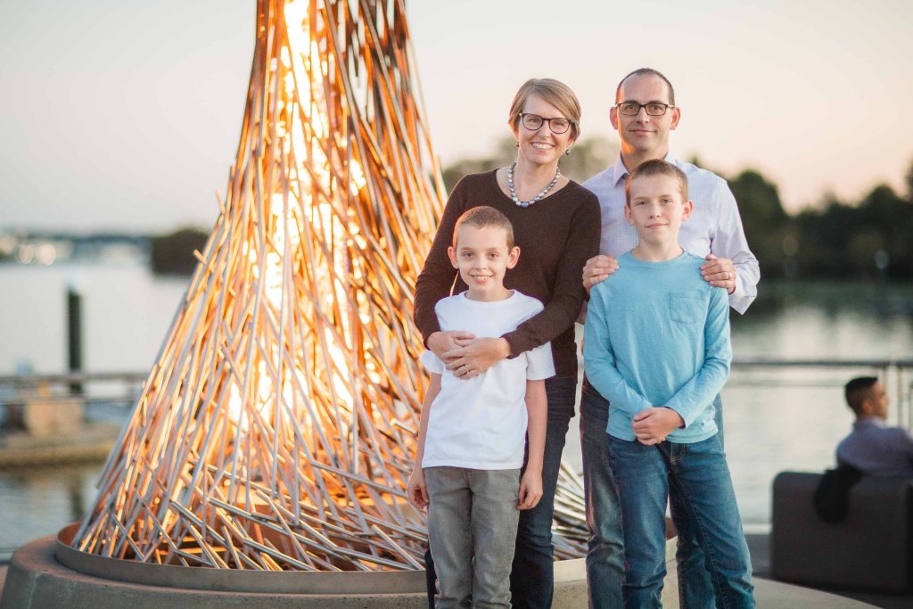 A family posing for a photo in front of a fire sculpture at District Wharf in Washington DC.