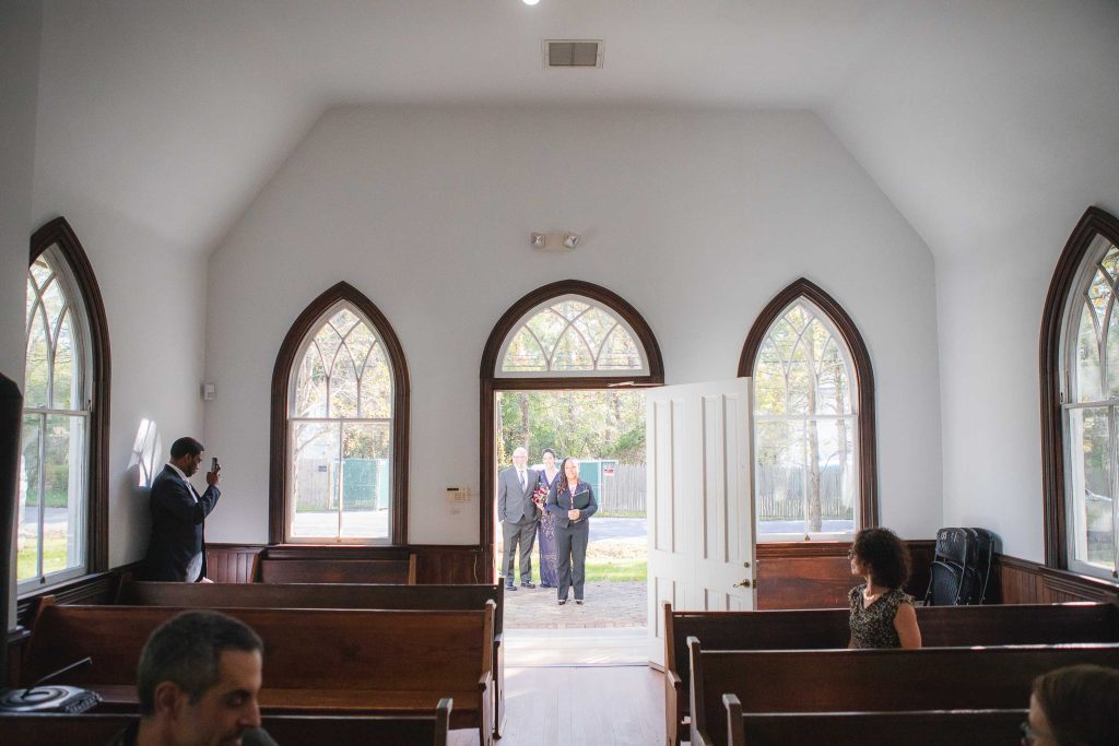 A bride and groom stand in front of a pew at Dorsey Chapel in Maryland.