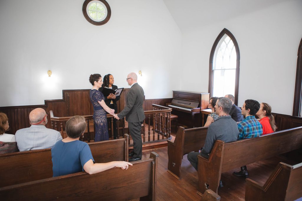A wedding ceremony in the Glenn Dale church with people sitting in the pews.
